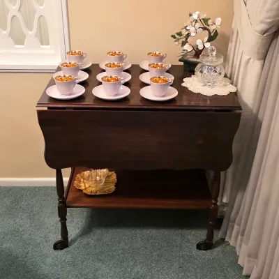 Vintage drop-leaf serving table with lower shelf, displayed with Danish gold-interior cups and saucers.