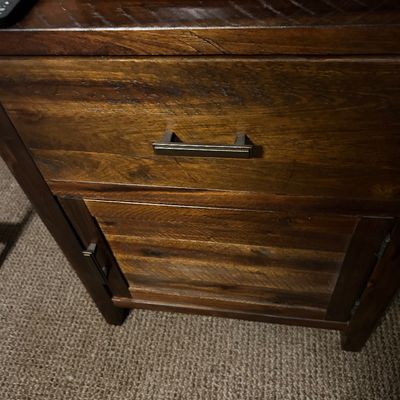 Sale Photo Thumbnail #93: Rustic dark wood nightstand featuring a single drawer with a modern metal pull and a lower cabinet door.