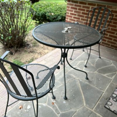 Sale Photo Thumbnail #6: Black wrought iron bistro set featuring a round mesh-top table and two matching chairs with slatted backs.