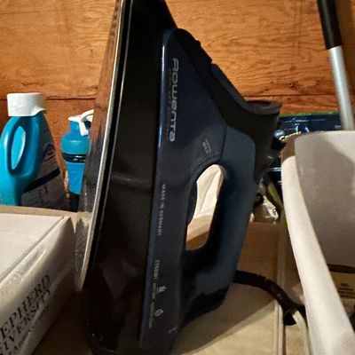 Sale Photo Thumbnail #48: Rowenta steam iron in blue and black, made in Germany, shown standing upright on a shelf.