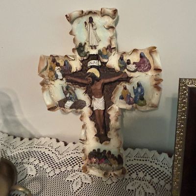 Sale Photo Thumbnail #25: Ornate resin wall cross featuring a central crucifix surrounded by painted scenes from the life of Jesus Christ, designed with a faux-parchment scroll edge.