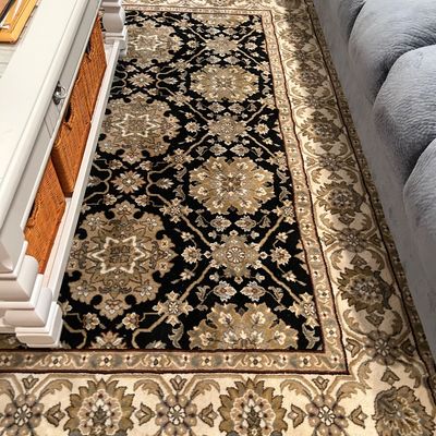 Sale Photo Thumbnail #71: Traditional area rug featuring an ornate floral medallion pattern in black, beige, and olive green tones, positioned between a white coffee table and a grey sofa.