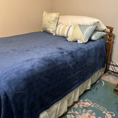 Sale Photo Thumbnail #113: Twin-sized bed with a wooden headboard, dressed in a blue textured blanket, cream bed skirt, and an assortment of decorative throw pillows.