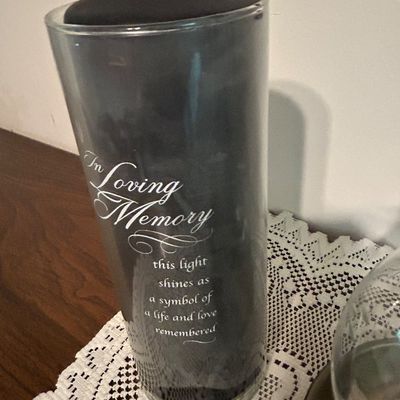 Sale Photo Thumbnail #26: In Loving Memory memorial candle holder, featuring a tall cylindrical glass sleeve with white script lettering and a black candle insert.