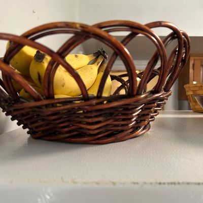 Sale Photo Thumbnail #9: Dark brown woven wicker fruit basket with a looped rim design, holding bananas.