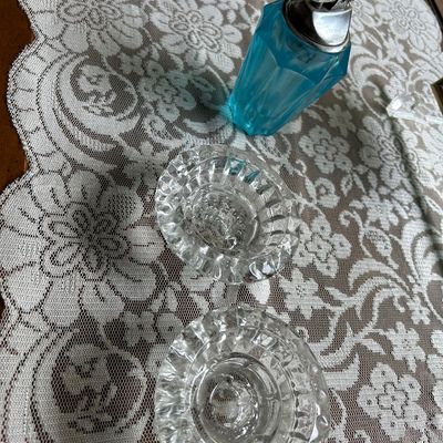 Sale Photo Thumbnail #136: Vintage blue glass table lighter alongside two small cut-glass ashtrays, displayed on a white lace runner.