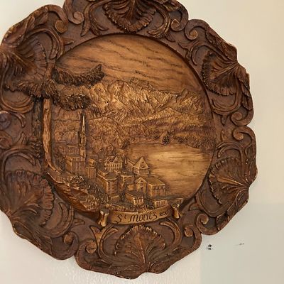 Sale Photo Thumbnail #130: Vintage carved wood-look resin wall plaque depicting a relief scene of St. Moritz, Switzerland, featuring an ornate floral border.