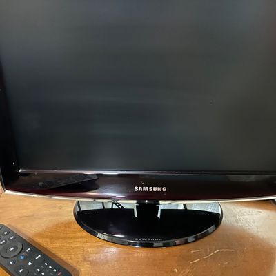 Sale Photo Thumbnail #112: Samsung flat-screen television with a dark red bezel and matching remote control, circa late 2000s.