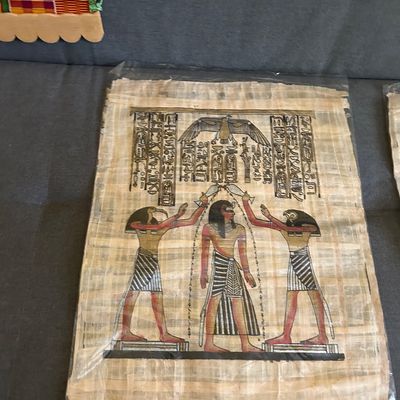 Sale Photo Thumbnail #122: Egyptian papyrus painting depicting a pharaoh flanked by Thoth and Horus, rendered in traditional black, red, and gold pigments.
