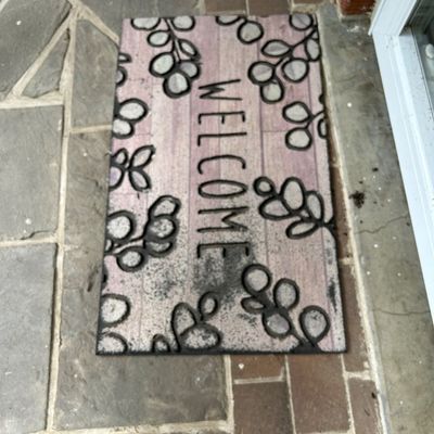 Sale Photo Thumbnail #36: Rectangular welcome mat featuring a pink wood-grain background, black leaf patterns, and "WELCOME" printed in the center.