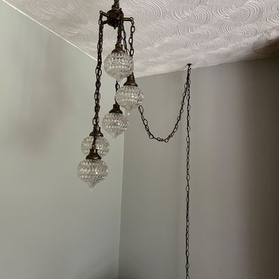 Sale Photo Thumbnail #139: Vintage mid-century swag chandelier featuring five tiered, textured clear glass globes suspended from brass chains.