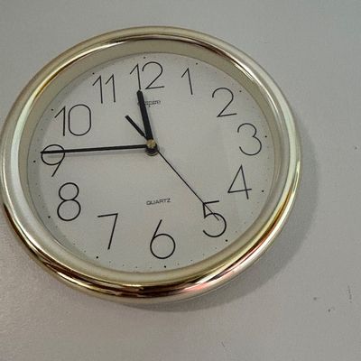 Sale Photo Thumbnail #42: Empire Quartz round wall clock with a gold-tone plastic frame and a white face featuring large black numerals.