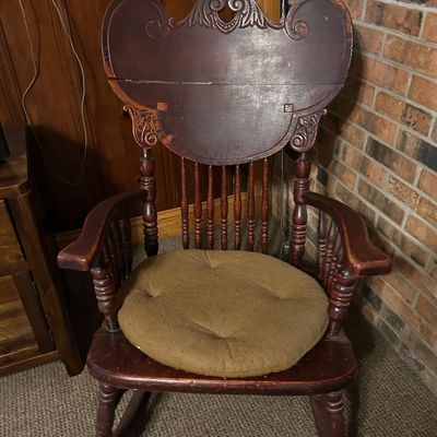 Sale Photo Thumbnail #92: Antique wooden rocking chair with a carved, high-back splat, spindle supports, and a round fabric seat cushion.