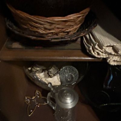Sale Photo Thumbnail #29: Assorted vintage household items on wooden shelves, including woven baskets, folded linens, a glass beer stein with a pewter lid, and decorative glassware.