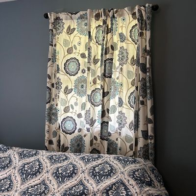 Sale Photo Thumbnail #103: Contemporary floral print curtains in shades of blue, teal, and grey on a cream background, shown hanging on a black rod alongside a coordinating patterned quilt.