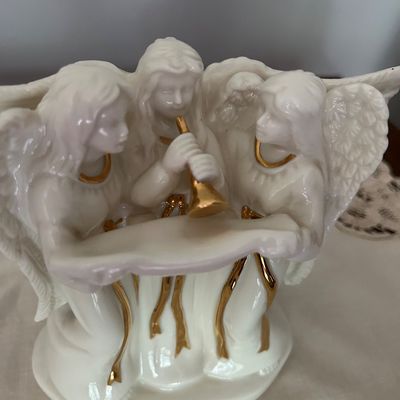 Sale Photo Thumbnail #134: Lenox porcelain angel trio figurine featuring three white-glazed angels with gold-gilded accents, one playing a horn and two holding a scroll.
