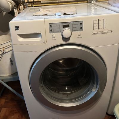 Sale Photo Thumbnail #60: Kenmore front-loading washing machine with Vibration Guard, featuring a white exterior and silver-trimmed door.