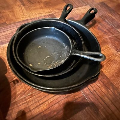 Sale Photo Thumbnail #53: Stack of three vintage cast iron skillets in graduated sizes, showing some wear and seasoning.