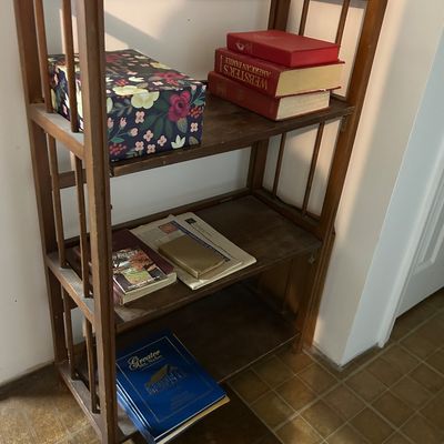 Sale Photo Thumbnail #78: Vintage mission-style folding wooden bookshelf holding books and a floral decorative box.