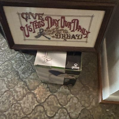 Sale Photo Thumbnail #24: Framed cross-stitch sampler featuring the phrase "Give Us This Day Our Daily Bread" in a dark wood frame, shown resting on a Globe brand box.