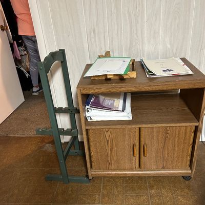 Sale Photo Thumbnail #82: Mid-century style faux-wood laminate rolling cart with an open shelf and lower double-door cabinet, shown next to a green wooden folding stand.