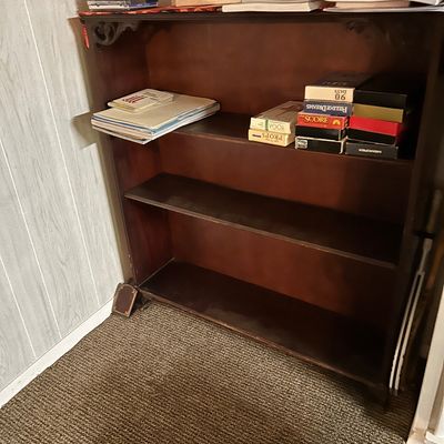 Sale Photo Thumbnail #94: Vintage dark wood three-shelf bookcase featuring decorative carved corbels at the top corners, holding books and media.
