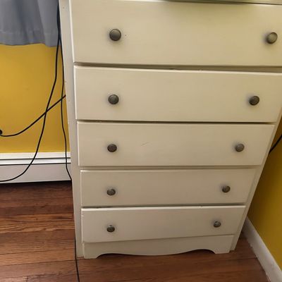 Sale Photo Thumbnail #109: Five-drawer wooden chest of drawers painted off-white, featuring simple round metal knobs and a scalloped bottom apron.