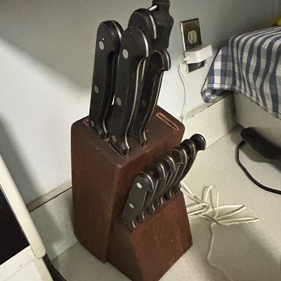 Sale Photo Thumbnail #32: Vintage wooden knife block set containing an assortment of kitchen and steak knives with black riveted handles.