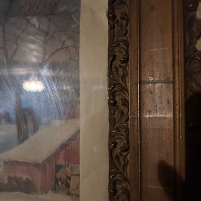 Sale Photo Thumbnail #90: Detail of an ornate, carved wooden picture frame next to a winter landscape painting.