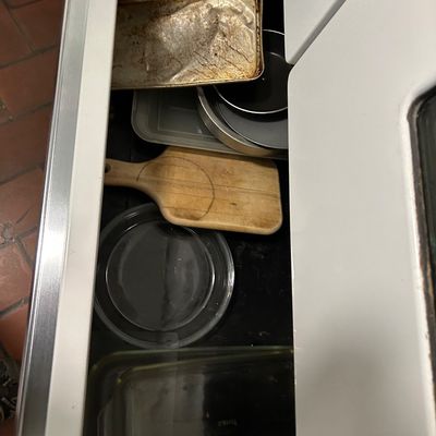 Sale Photo Thumbnail #21: Assorted kitchen bakeware and accessories stored in a drawer, including glass baking dishes, a wooden cutting board, and metal pans.