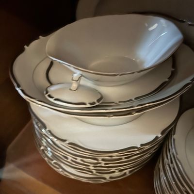 Sale Photo Thumbnail #153: Vintage white porcelain dinnerware set featuring a gravy boat and stacked plates with elegant silver trim.