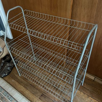 Sale Photo Thumbnail #106: Four-tier grey wire shoe rack with a tubular metal frame, designed for closet or entryway organization.