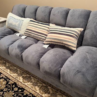 Sale Photo Thumbnail #72: Plush grey channel-tufted sofa with textured fabric, accompanied by three decorative throw pillows.