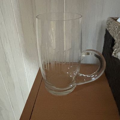 Sale Photo Thumbnail #44: Clear glass beer mug featuring an etched design on the side, resting on a wooden surface.