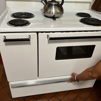 Sale Photo Thumbnail #20: Vintage Frigidaire white electric range with four coil burners, a double oven configuration, and a stainless steel tea kettle resting on top.