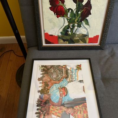 Sale Photo Thumbnail #125: Two framed artworks, including an oil painting of red roses in a glass vase and a framed photograph depicting a group of women in vibrant traditional attire.