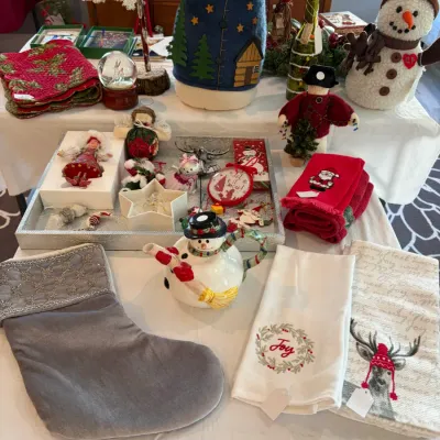 Sale Photo Thumbnail #194: Assortment of Christmas holiday decorations featuring a grey velvet stocking with silver beaded trim, a snowman teapot, embroidered hand towels, and various festive figurines and ornaments.