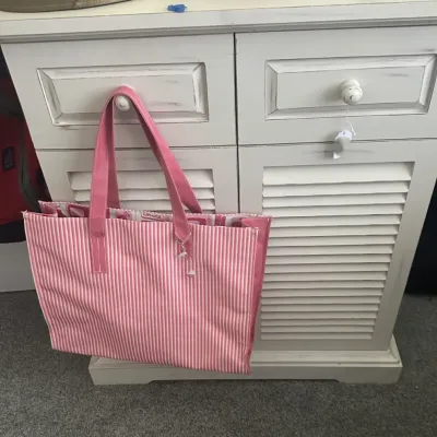 Sale Photo Thumbnail #80: White distressed-finish wooden cabinet with louvered doors and two drawers, shown with a pink and white striped tote bag hanging from a drawer knob.