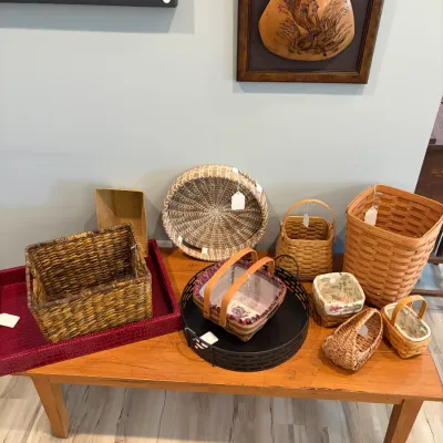 Sale Photo Thumbnail #86: Assortment of woven baskets in various shapes and sizes, including Longaberger-style baskets, displayed on a wooden coffee table alongside decorative trays.
