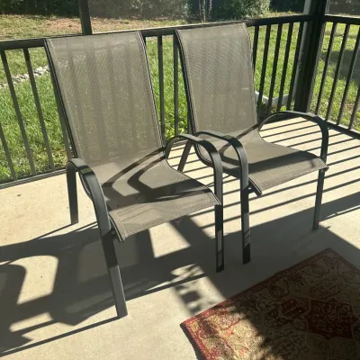 Sale Photo Thumbnail #171: Pair of modern outdoor patio armchairs featuring dark metal frames and breathable brown mesh sling seating.