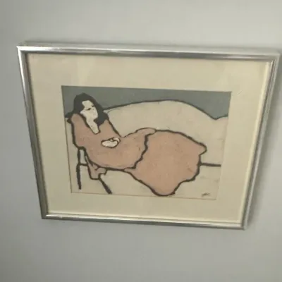 Sale Photo Thumbnail #27: Framed mid-century modern style art print depicting a reclining figure in muted pink and grey tones, housed in a silver-toned metal frame.