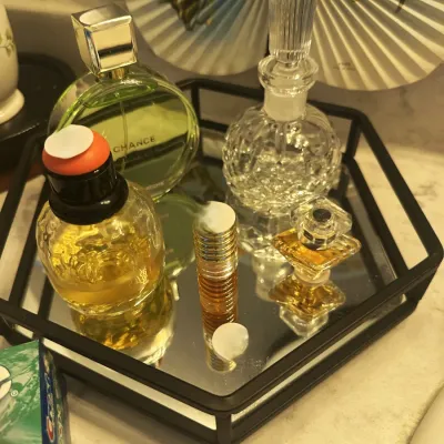 Sale Photo Thumbnail #140: Assorted vintage and designer perfume bottles, including Chanel Chance, displayed on a hexagonal mirrored vanity tray.