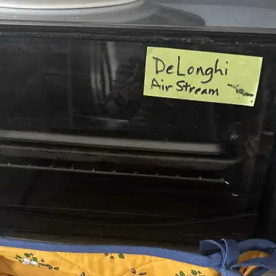 Sale Photo Thumbnail #11: DeLonghi Air Stream countertop toaster oven in black, featuring digital controls and multiple cooking functions.