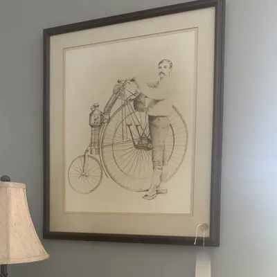 Sale Photo Thumbnail #26: Large framed vintage-style sketch depicting a man with a high-wheel penny-farthing bicycle, presented in a dark wood frame with a wide mat.