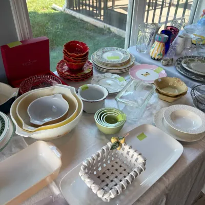 Sale Photo Thumbnail #108: An assortment of vintage and modern kitchenware, featuring Pyrex nesting bowls, decorative ceramic plates, a Waterford Crystal box, and a white woven ceramic basket with lemon accents.