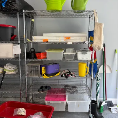 Sale Photo Thumbnail #149: Classic red Radio Flyer wagon parked in front of a rolling chrome wire shelving unit stocked with household goods, plastic storage bins, and gardening accessories.