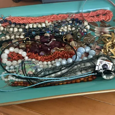 Sale Photo Thumbnail #99: Assortment of vintage costume jewelry, including beaded necklaces, coral strands, and bracelets, displayed on a turquoise tray.