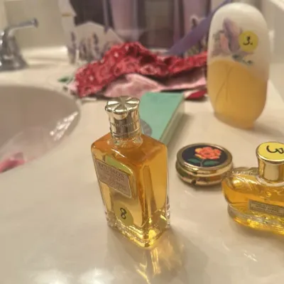 Sale Photo Thumbnail #138: Vintage perfume bottles including Ecusson and Wind Song, displayed on a bathroom counter alongside a lavender bath gift set.