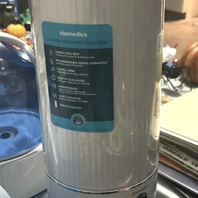 Sale Photo Thumbnail #19: Homedics cool mist ultrasonic humidifier, featuring a white cylindrical body with a digital display, wooden feet, and original product labels.