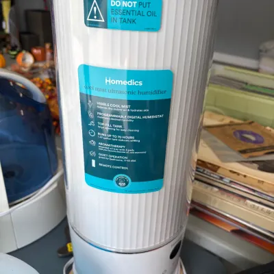 Sale Photo Thumbnail #13: Homedics cool mist ultrasonic humidifier featuring a modern white ribbed tower design with a top-fill tank. The unit appears in excellent condition with original retail stickers still attached.